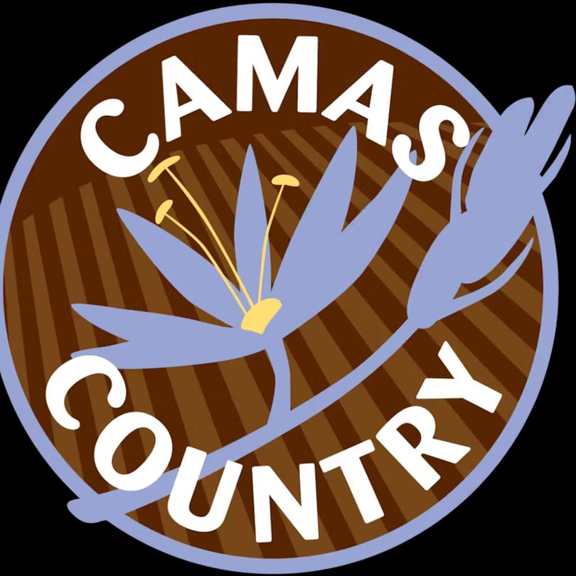 Camas Country logo, a brown circle with a light blue flower and "Camas Country" text.